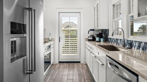 Una cocina moderna con electrodomésticos de acero inoxidable, un ventanal y vista a una casa.