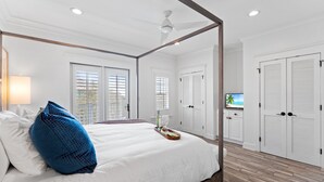 Un dormitorio con cama con dosel, paredes blancas y suelo de madera.
