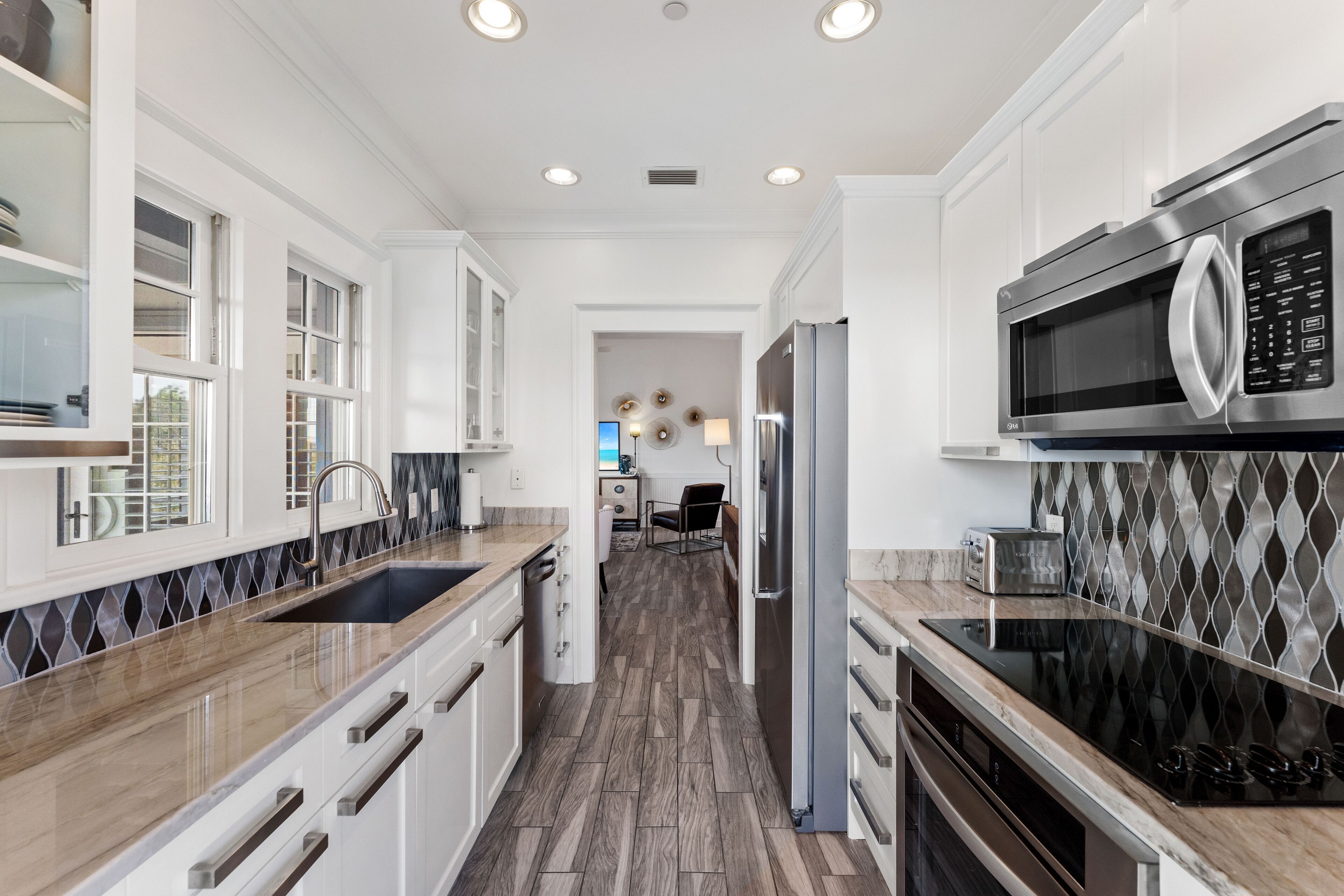 A modern kitchen with white cabinetry, a stainless steel microwave, and a black stovetop.