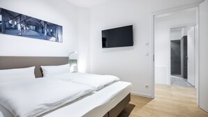 Ein modernes Schlafzimmer mit einem großen Bett, einem Flachbildfernseher und einem Bild an der Wand.