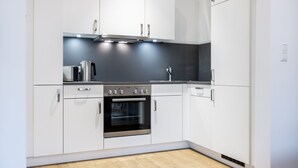 Eine moderne Küche mit weißen Schränken, einem Edelstahlbackofen und einer schwarzen Arbeitsplatte.