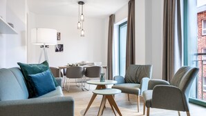 Ein modernes Wohnzimmer mit einer Couch, Sesseln, einem Esstisch und einer Lampe.