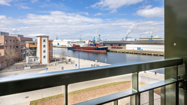 A view of a harbor with a large cargo ship docked, buildings, and a clear sky. - Great south-facing harbor apartment with a direct view of Wismar's old harbor (Hansestadt Wismar)