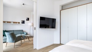 A modern hotel room with a bed, a TV mounted on the wall, a sofa, and a small table. - Stilvolles, Modernes Hafenapartment mit Tollem Blick auf den Alten Hafen Wismars (Hansestadt Wismar)