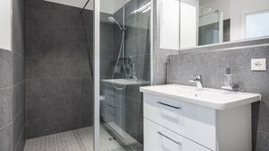 A modern bathroom with a glass-enclosed shower, a white vanity with a sink, and a large mirror above the vanity. - Stilvolles, Modernes Hafenapartment mit Tollem Blick auf den Alten Hafen Wismars (Hansestadt Wismar)