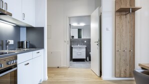 A modern kitchen with white cabinets, a stainless steel range hood, and a built-in oven.