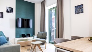 A modern living room with a flat-screen TV, a dining table, and a sofa. - Helles, Geschmackvolles Apartment in Erstklassiger Lage am Seehafen von Wismar (Hansestadt Wismar)
