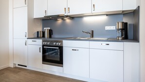 Una cocina moderna con armarios blancos, electrodomésticos de acero inoxidable y un horno empotrado.