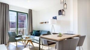 A modern living room with a sofa, chairs, a dining table, and a large window.