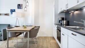 A modern kitchen with white cabinets, stainless steel appliances, and pendant lighting.