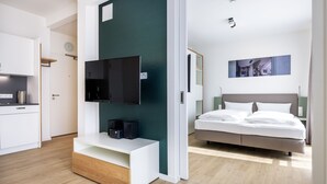 A modern hotel room with a flat-screen TV, a bed, and a small desk area.