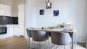 A modern kitchen with white cabinets, a wooden countertop, and a dining area with two grey chairs and a wooden table.