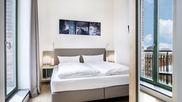 Una habitación de hotel moderna con una cama grande, vistas de la ciudad y un cuadro en la pared.