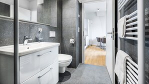 Un baño moderno con lavamanos blanco, inodoro y espejo.