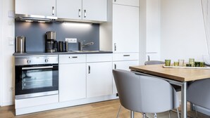 Una cocina moderna con armarios blancos, electrodomésticos de acero inoxidable y una mesa de comedor de madera con sillas.