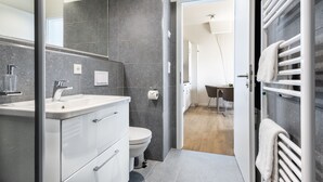 A modern bathroom with a large mirror, white vanity, and a shower area.