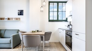 A modern kitchen with white cabinets, a built-in oven, and a window with a view of the sky.