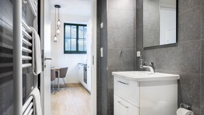A modern bathroom with a white sink, dark tiled walls, and a large mirror.