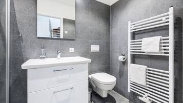 Un baño moderno con un tocador blanco, un inodoro y un perchero para toallas.