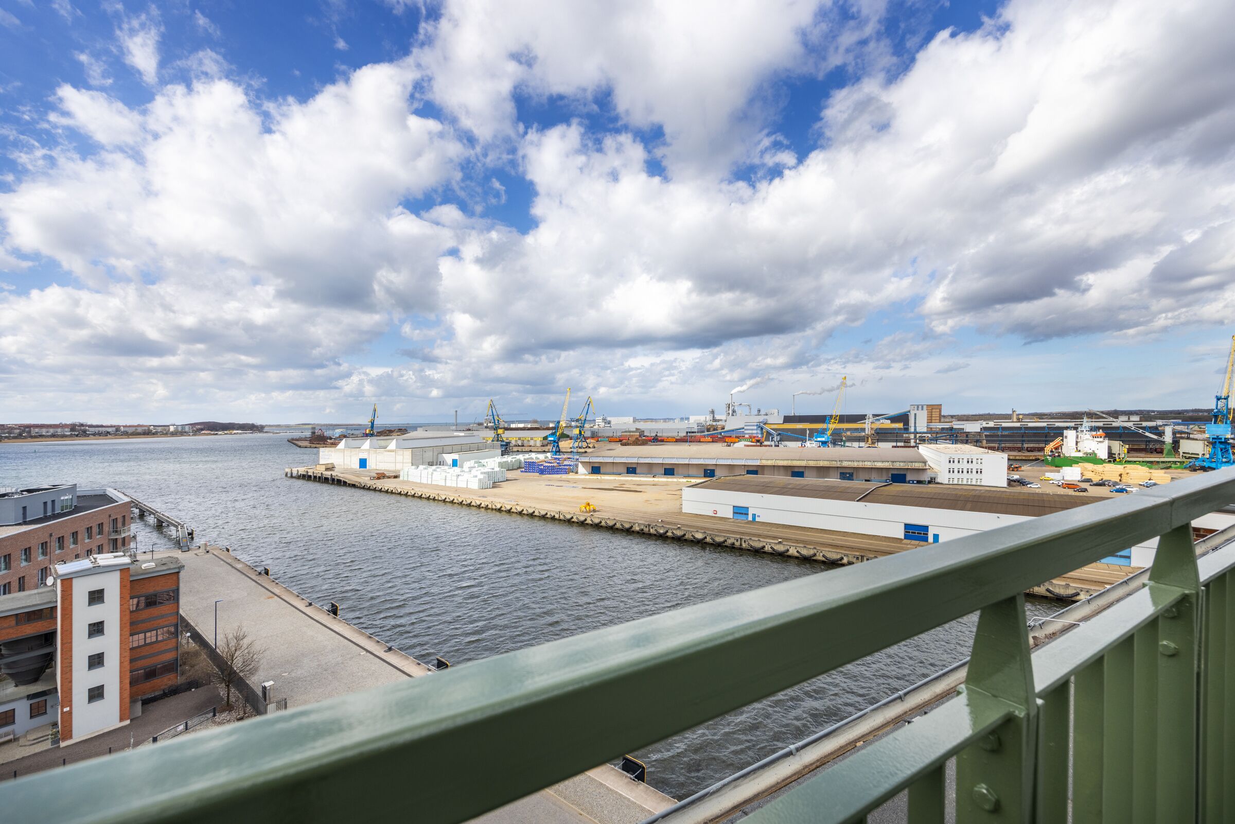A waterfront industrial area with cranes, warehouses, and a dock.