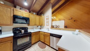 A kitchen with wooden cabinets, a black stove, a microwave, a sink, and a dishwasher. - Snowcreek Resort Vacation Rental 99 (Mammoth Lakes)