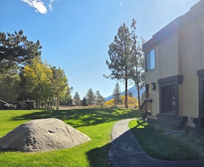 Un barrio residencial con una casa, una roca grande y una montaña al fondo.