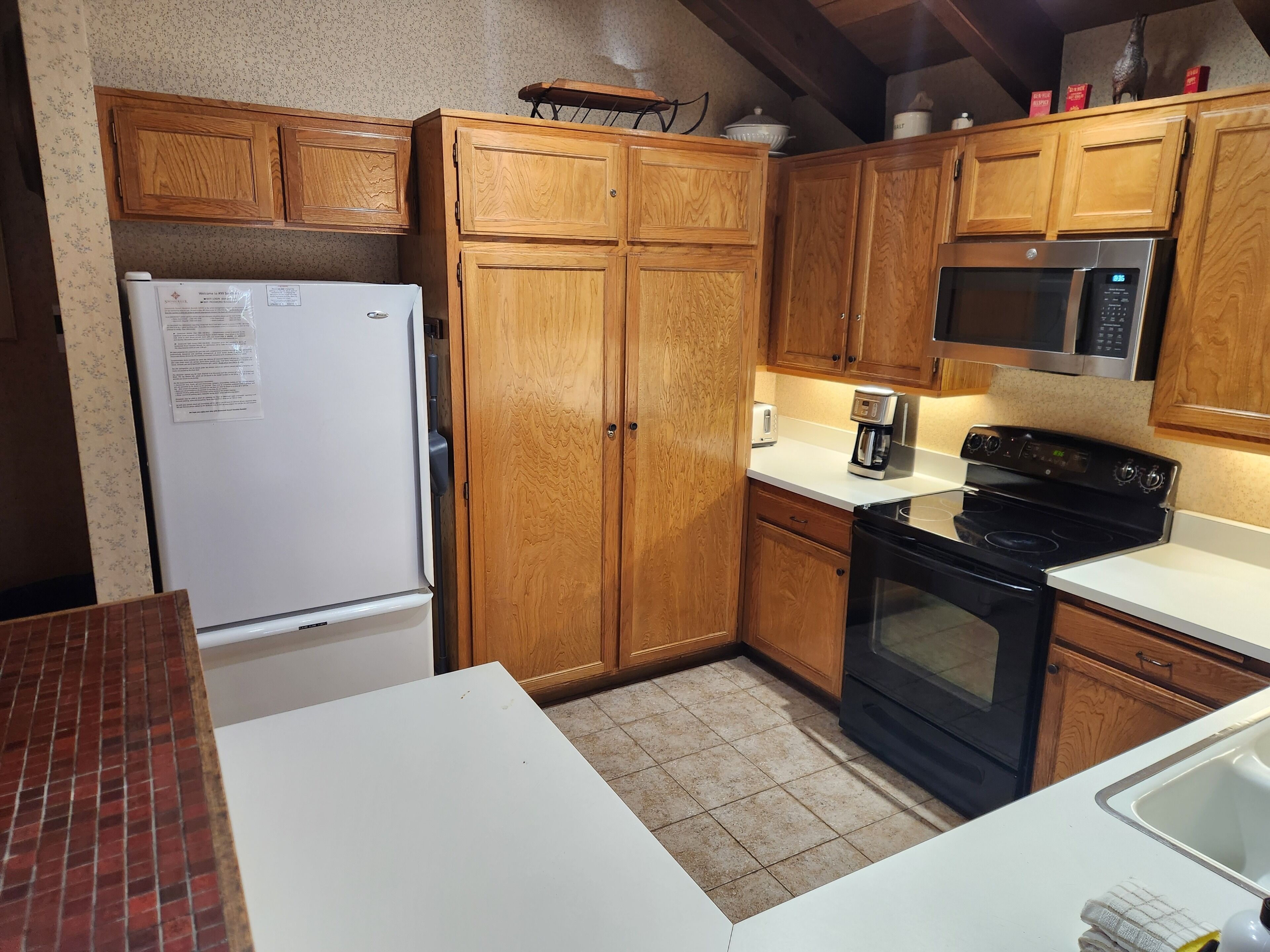 Une cuisine avec des meubles de rangement en bois, un réfrigérateur, un four à micro-ondes, une cuisinière et un évier.