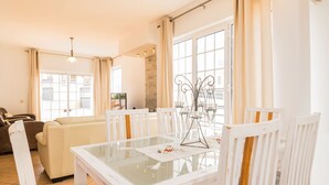 A dining area with a glass table, white chairs, and a chandelier. - Solis Villa, Albufeira, Algarve (Albufeira)