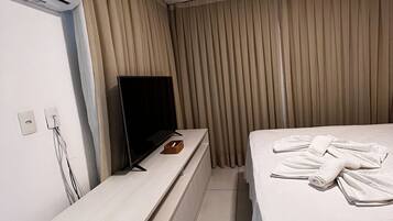 Ein Hotelzimmer mit einem Bett, einem Fernseher auf einem Schrank, einem kleinen Tisch und einer Klimaanlage.