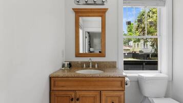 Ein Badezimmer mit einem Holzkonsolenunterschrank, einem Waschbecken, einem Spiegel und einer Toilette.