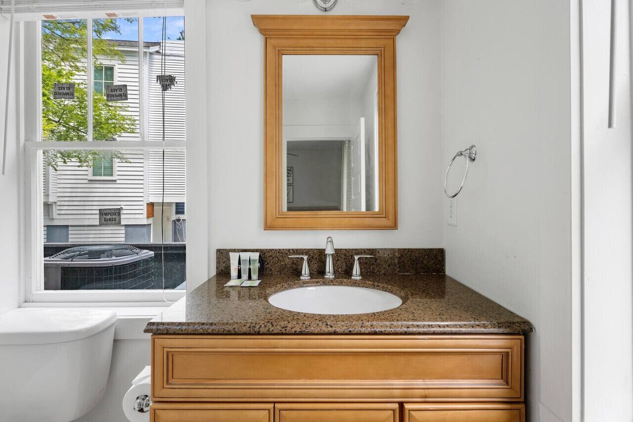 Une salle de bain avec un lavabo blanc, un meuble-lavabo en bois et un grand miroir.