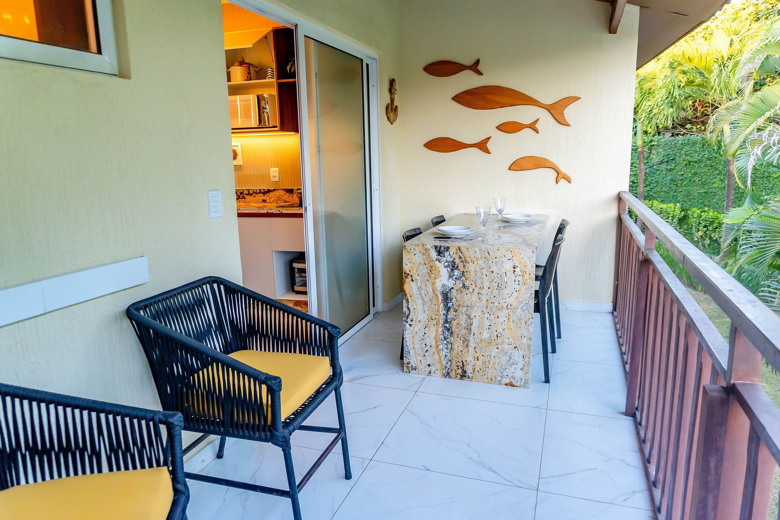 A balcony with a table set for dining, chairs, and a wall with fish decorations.