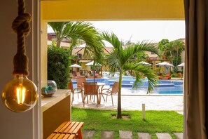 A view of a pool area with chairs and umbrellas, a palm tree, and a hanging light fixture. - Solar Água Pipa- Summer Pipa (Tibau do Sul)
