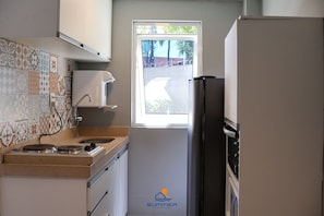 A compact kitchen with a window, a stove, and a refrigerator.
