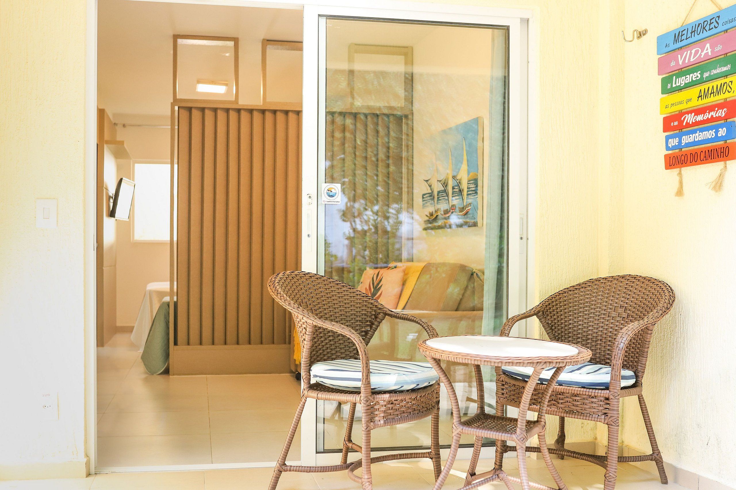 A room with wicker furniture, a glass door, and a wall with colorful signs.