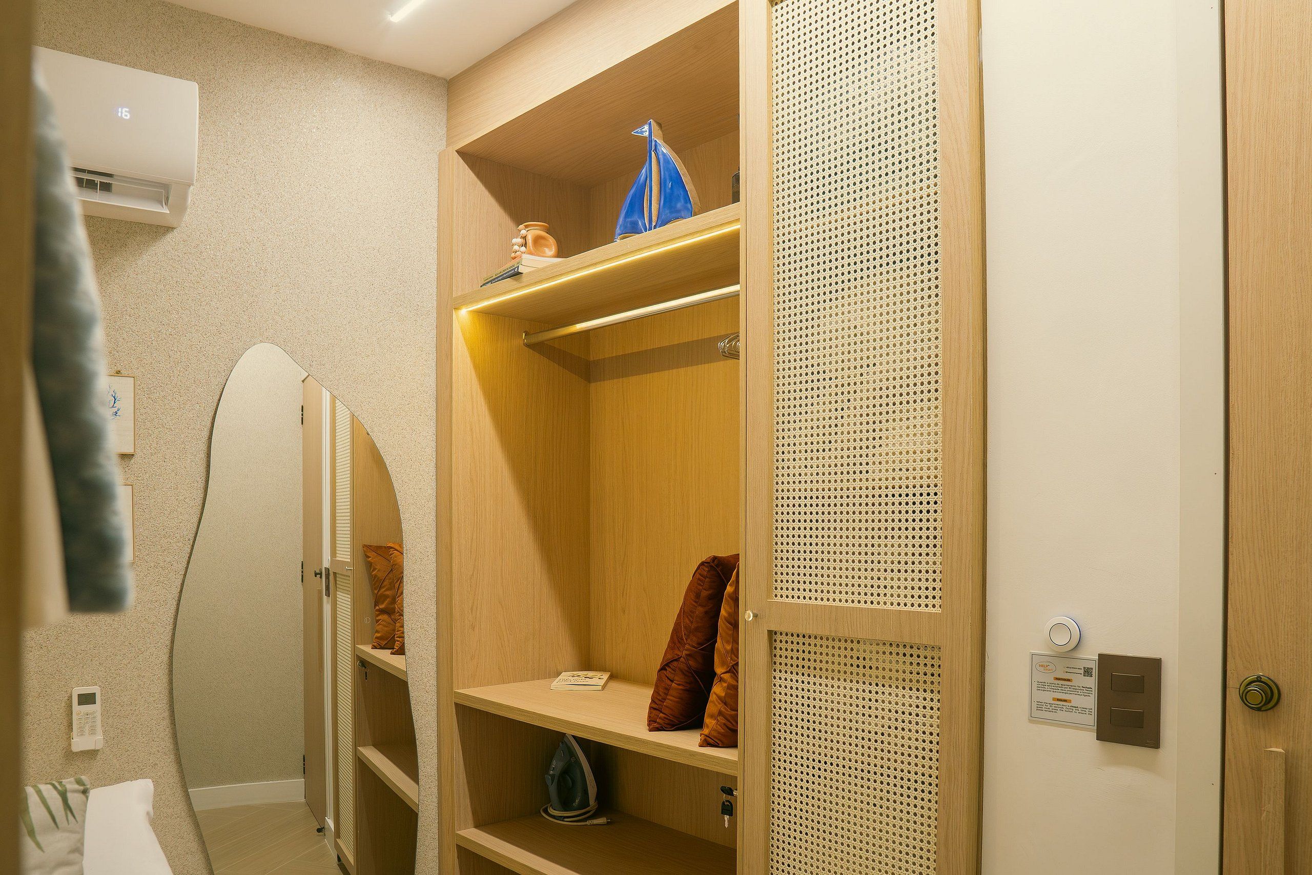 Een houten garderobe met planken, een kledingroede en een spiegelende kastdeur.