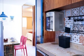 A kitchenette with a water dispenser, a black trash bin, and a tiled backsplash.