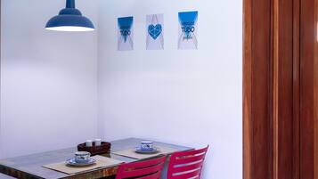 A dining area with a table, chairs, a hanging light, and wall decorations.