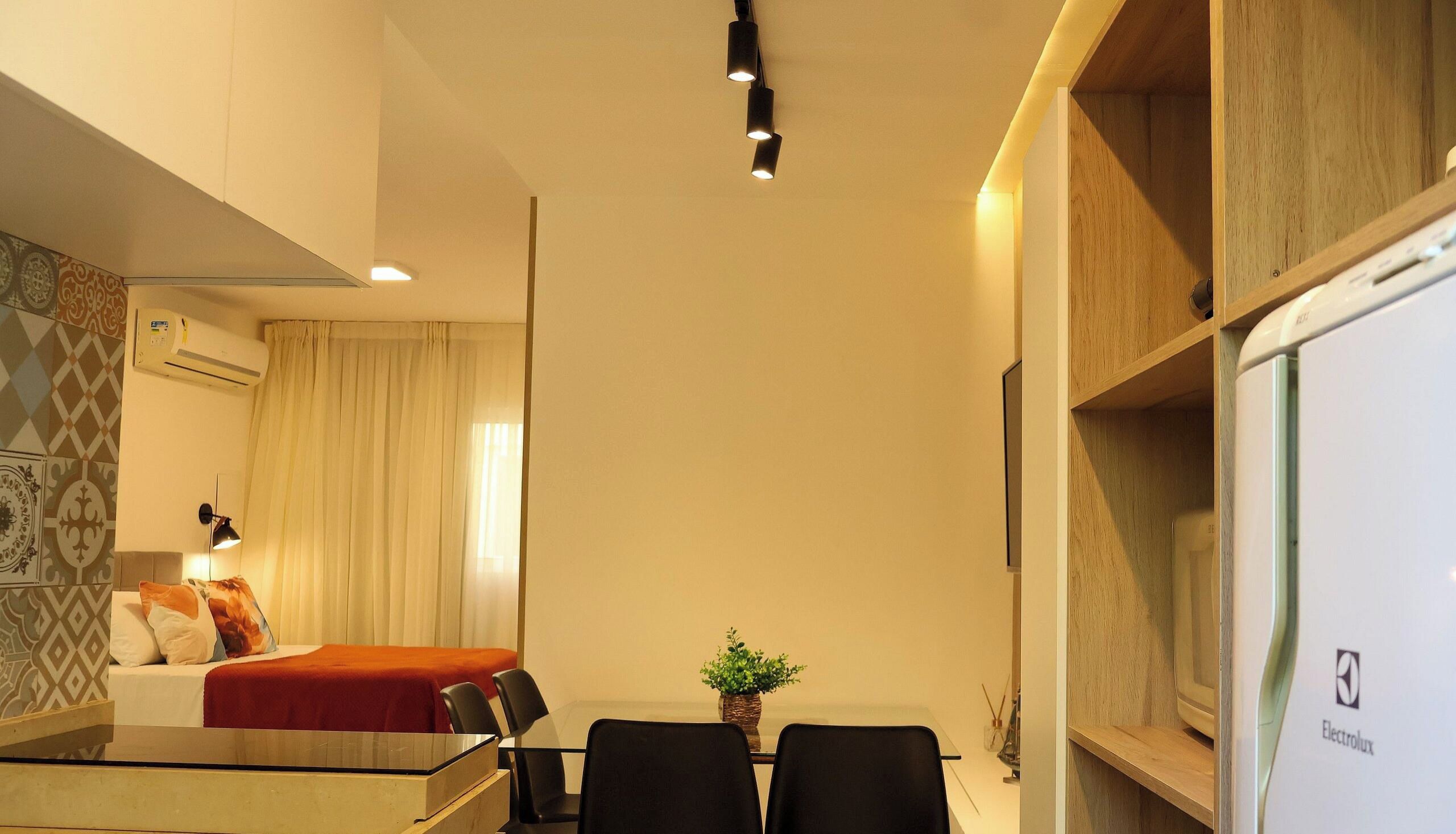 Une chambre d’hôtel compacte, équipée d’un lit, d’un bureau et d’une chaise. On peut voir une plante en pot sur le bureau.