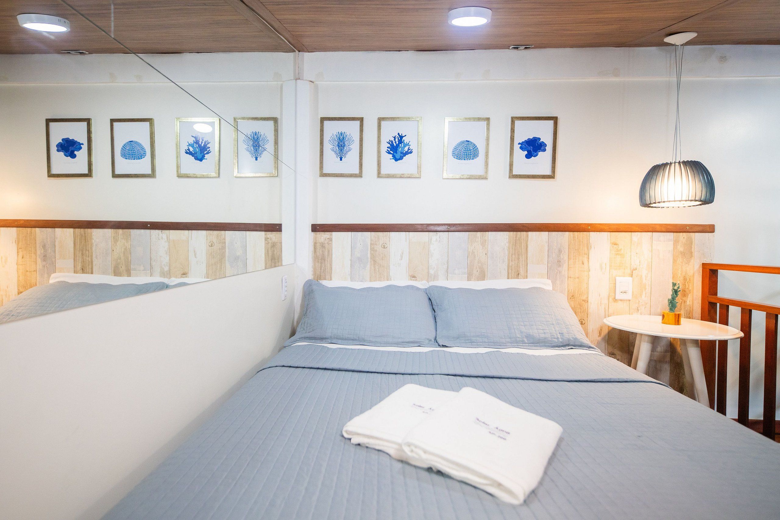 Une chambre d’hôtel avec un lit, une table ronde et des œuvres d’art accrochées au mur.
