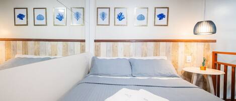 Une chambre d’hôtel avec un lit, une table ronde et des œuvres d’art accrochées au mur.