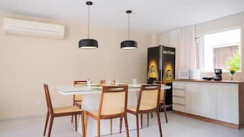 A dining area with a table and chairs, a kitchen with cabinets and appliances, and a window with curtains.