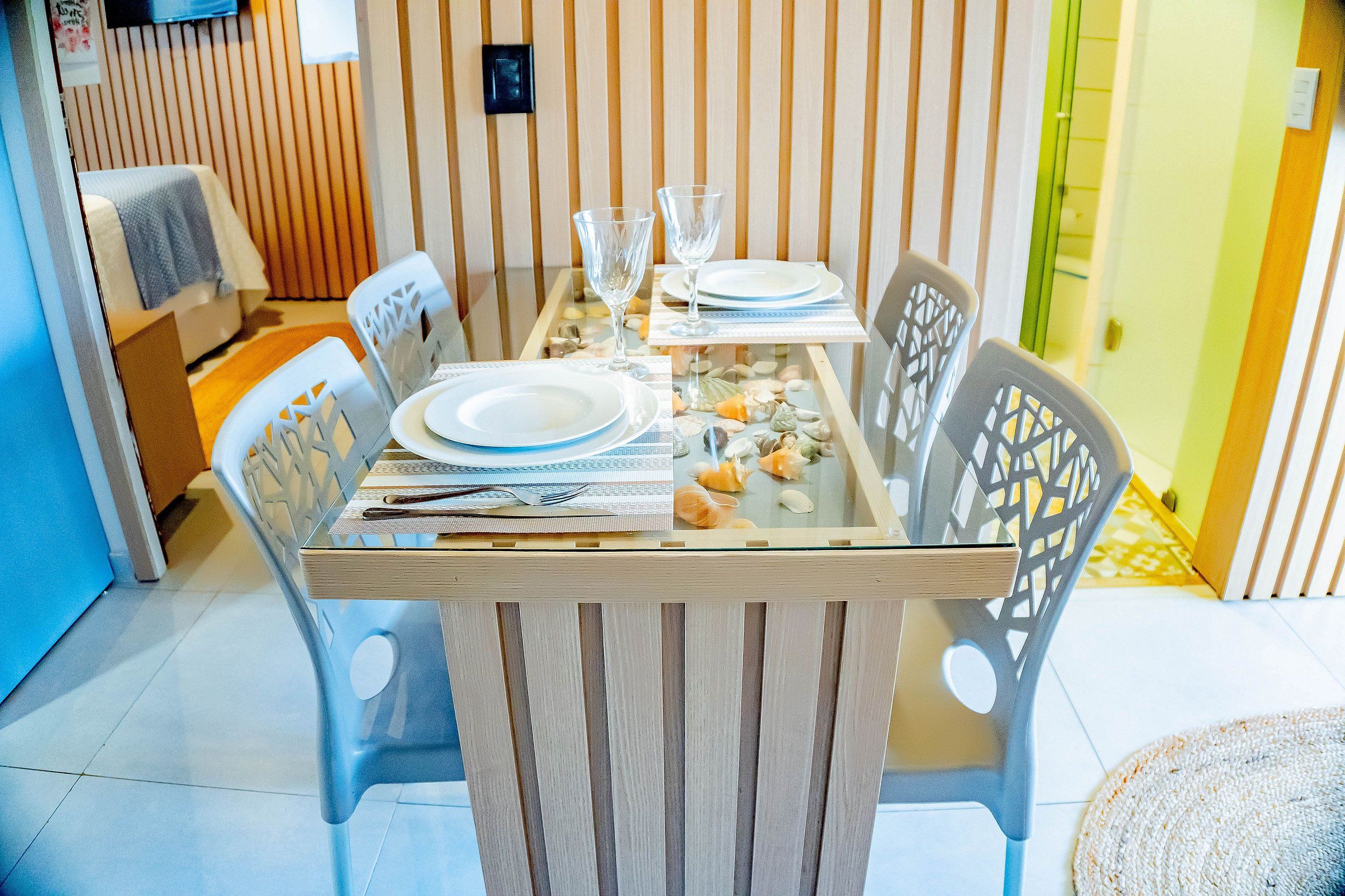 A dining table set with plates, cutlery, and glasses, surrounded by chairs with a geometric pattern.