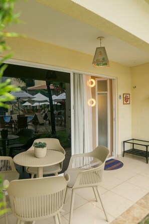 Un espacio patio con mesas y sillas redondas, un colgante de luz y vistas a mesas exteriores con sombrillas.