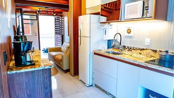 A compact kitchen with a built-in refrigerator, a microwave, and a sink with a faucet.