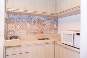 A kitchen with patterned backsplash, wooden cabinets, a sink, and a microwave. - Solar Água Pipa- Summer Pipa (Tibau do Sul)