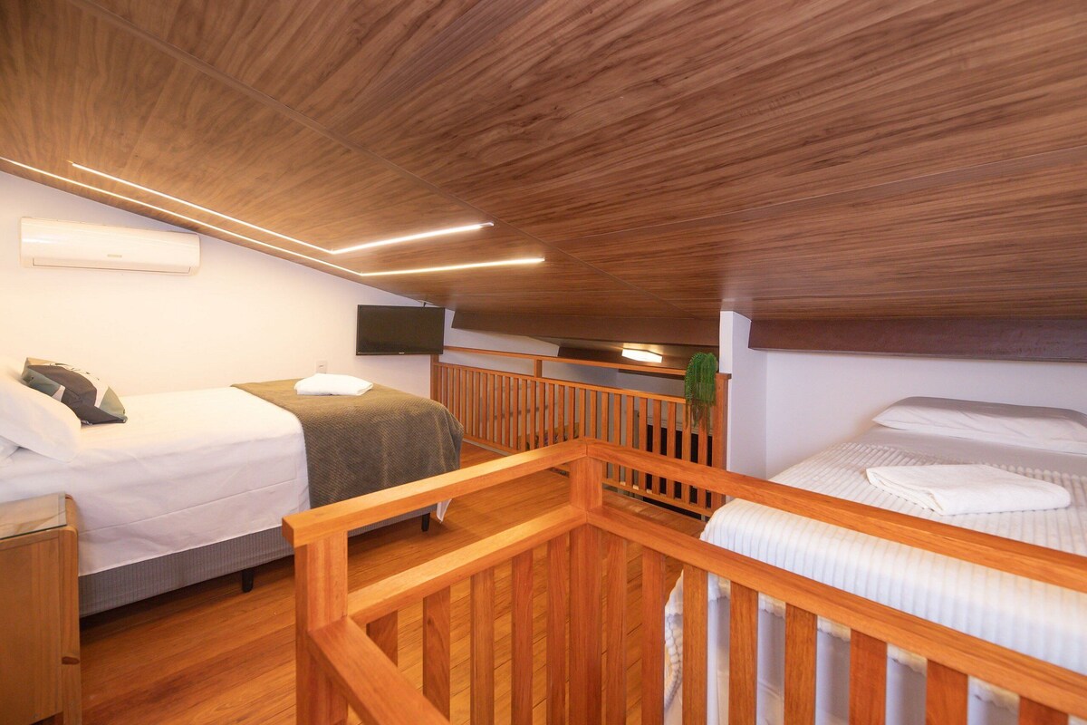 A room with two beds, wooden railings, a flat-screen TV, and an air conditioning unit.