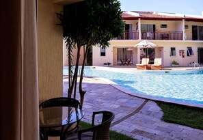 A pool area with lounge chairs, a table, and a small garden. - Solar Água Pipa- Summer Pipa (Tibau do Sul)