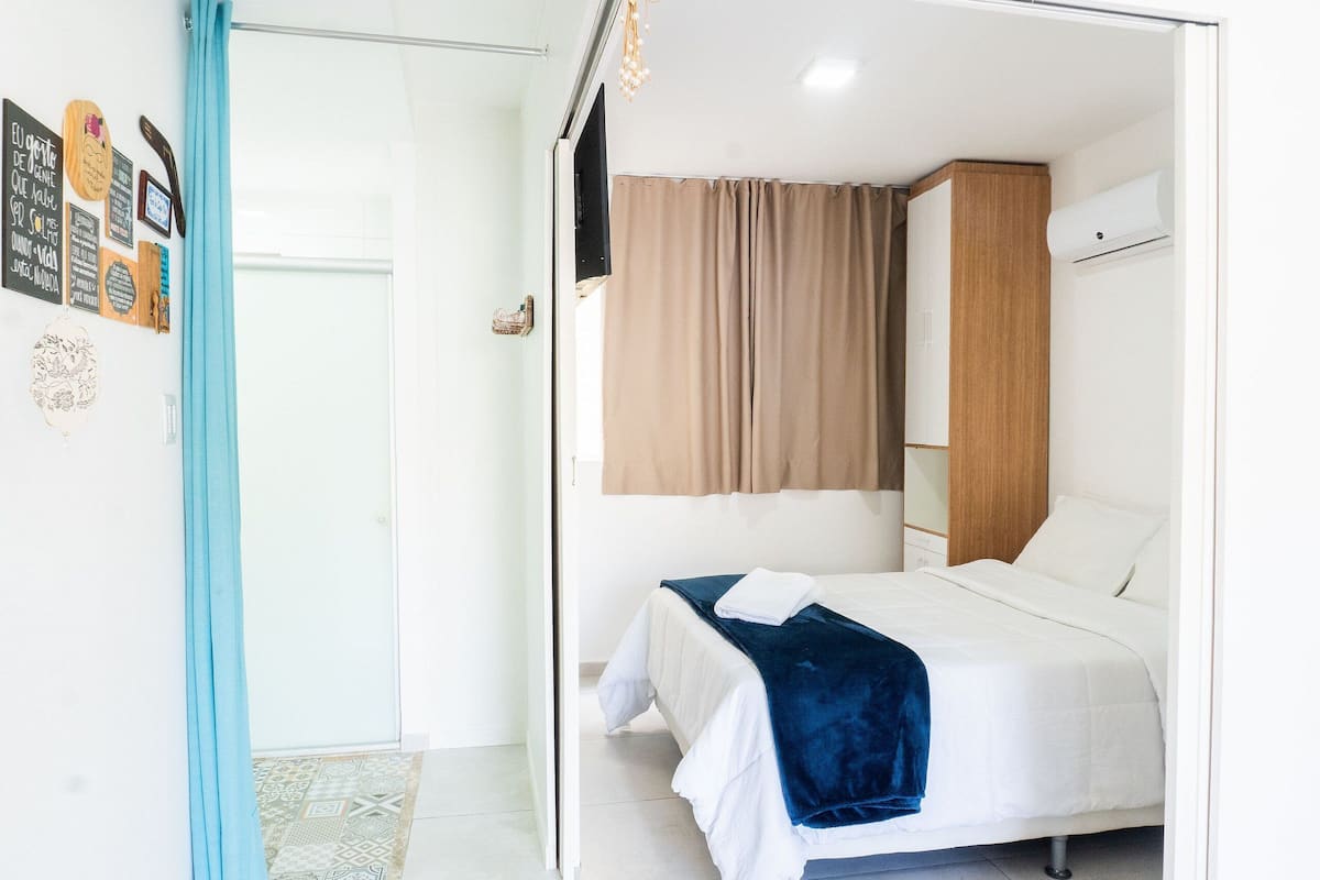 Un dormitorio con cama, armario, cortina y adornos en la pared.