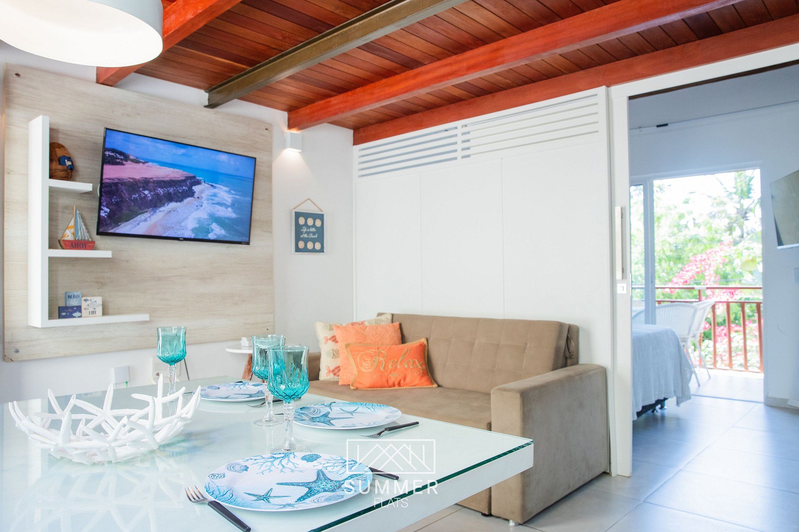 Una sala de estar moderna con televisor, una mesa de comedor de cristal y un sofá.